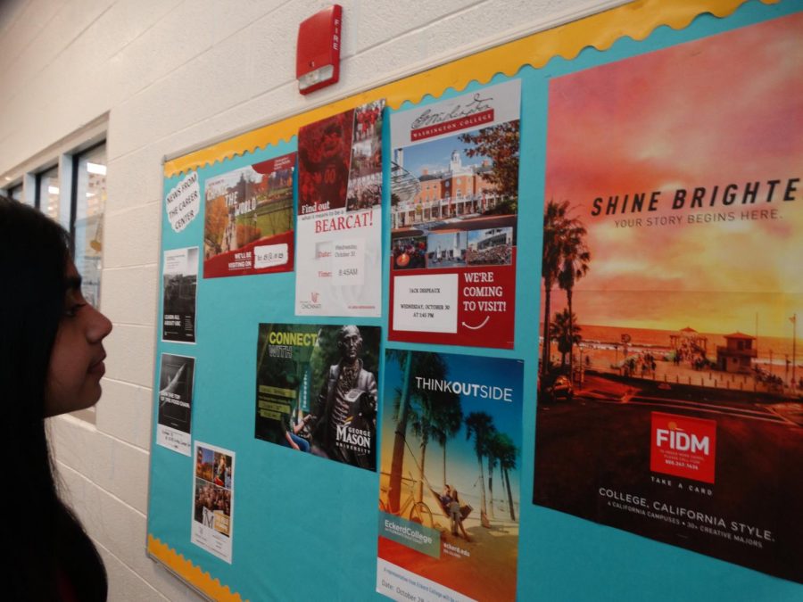 A student examines the different post-high school college options posted on the wall.