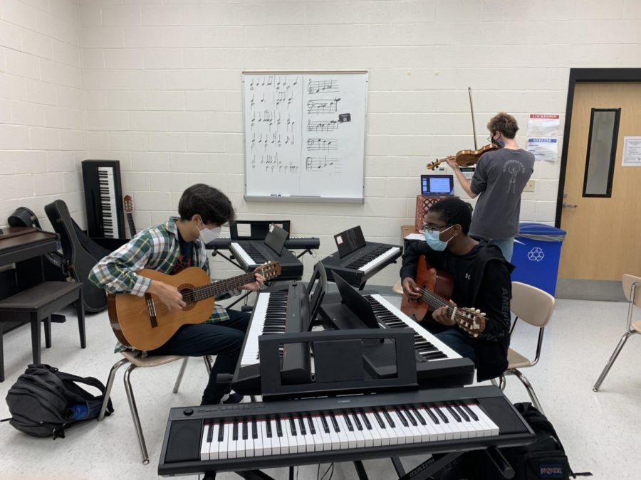 Seniors Patrick Kim (left) and David Louis (right) strum some tunes on their guitars at a Tri-M meeting.
