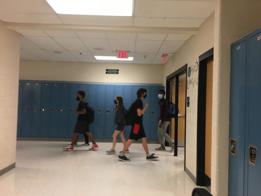 Students wearing masks walk through the language hallway to get to their next classes.