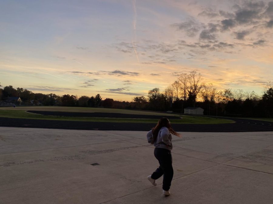 Senior EIC Delaney Crawley walks alongside the track as the sun sets after a long day of school and activities. She is often at school until the sun starts to go down. The school is always so busy so I appreciate the time of day when the hallways are empty and go quiet. Its peaceful, Crawley said.