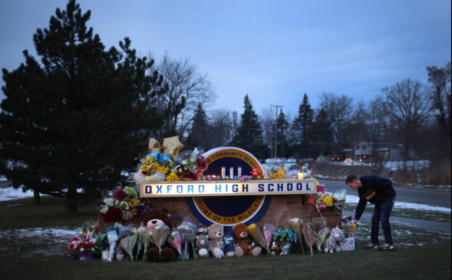 People+spread+flowers+and+like+items+around+the+entrance+of+Oxford+High+School+in+order+to+honor+the+victims+of+the+school+shooting.+