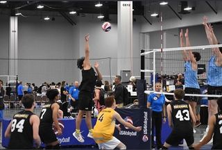 Volleyball player Alexander David-Corrales jumps to spike the ball at a tournament.