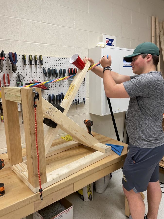 Senior Nicky Saffell puts the finishing touches on his catapult for his Advanced Design Application (ADA) class. Mr. Ackleys sixth period ADA class will be launching their catapults outside on the track Monday, May 22nd, and Tuesday May 23rd. Saffells catapult broke in testing when the hinge that holds the arm ripped out of the base board. Saffell is hopeful but cautious about how the catapult will perform, I think itll work until it splits, he said. Saffell thinks it will break again, history repeats itself, he said. 