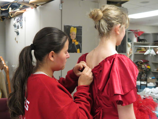 Sophomore costume member Natalie Morrison pins up senior cast member Katie Staudermans final dress in the show. “In the moment it’s a lot of pressure. You have to make sure everything looks good and you dont ruin their hair or makeup while also getting it done on time,” Morrison said. 

For fixing costumes the crew has their own room. It is set up with a closet to store items and counters to use when fixing costumes. There are drawers specifically used to keep extra accessories in and a rack with clothes that need to be fixed. They don’t just use the room to work with costumes though. When they are not doing quick changes or fixing costumes they use the room to hangout and complete homework. 