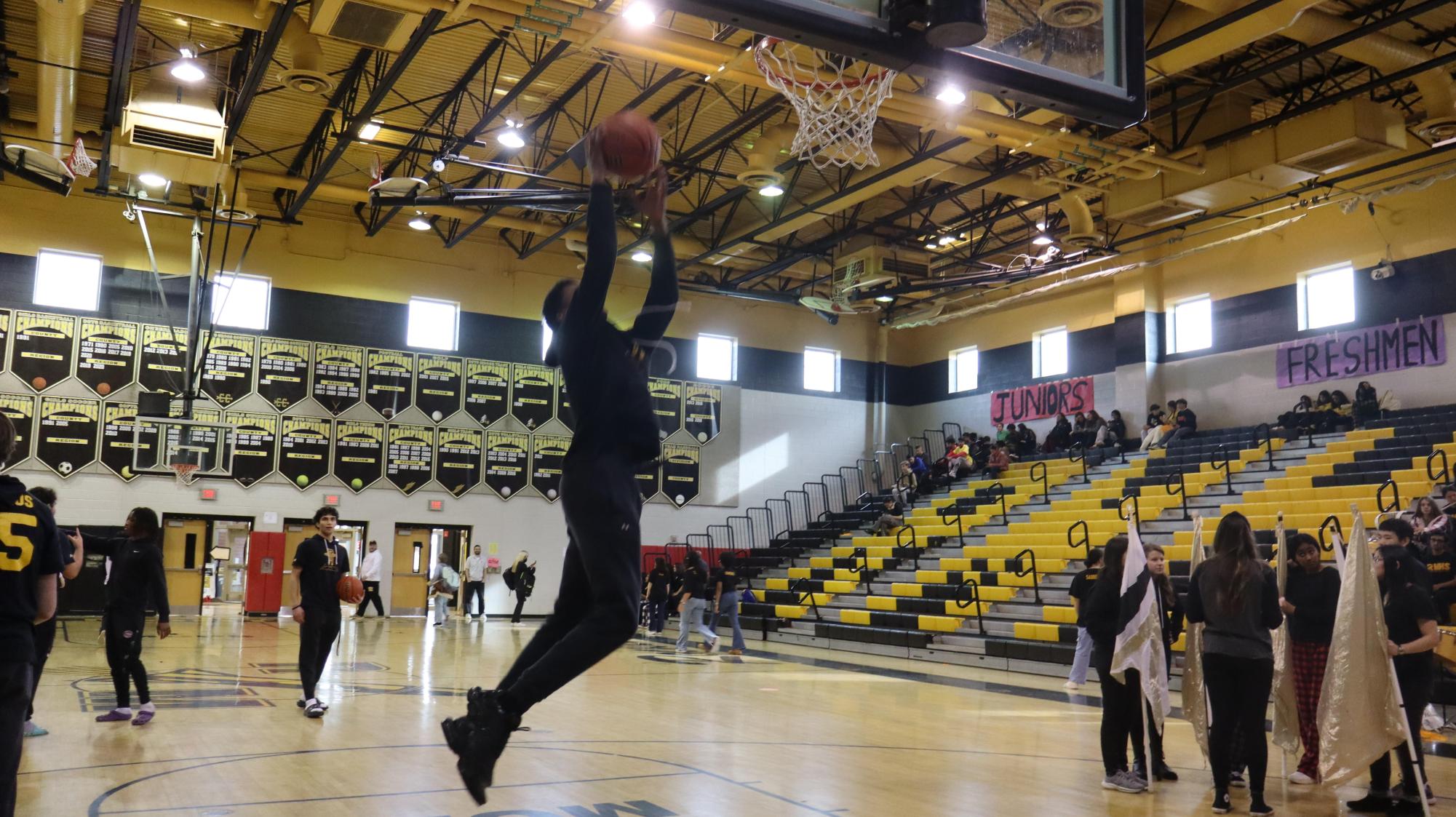 Senior Dante Mayo dunks on the basketball court during the transition between grades attending the pep rallies. Mayo performed for the underclassmen with his fellow teammates on the boys varsity basketball team.