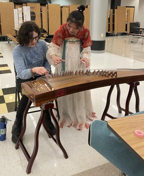 Sophomore Jing Yi Yang teaches senior Dasha Ucko to play the guzheng, a traditional Chinese string instrument.  