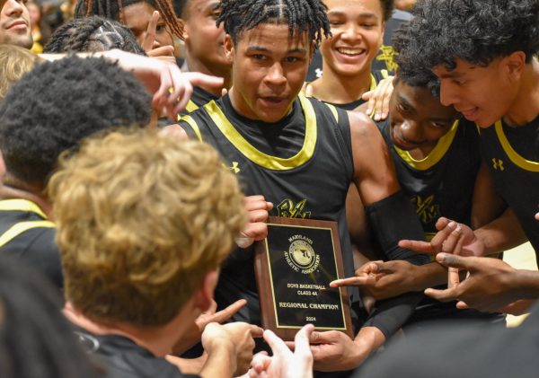 Wilson and the boys basketball team celebrate around the regional championship trophy. 