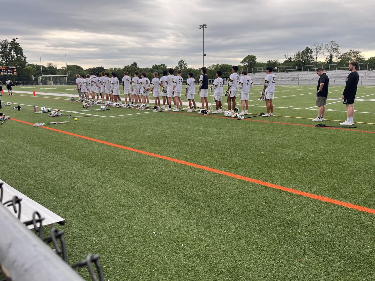 The varsity boys lacrosse teams stands together during the national anthem before their game.
