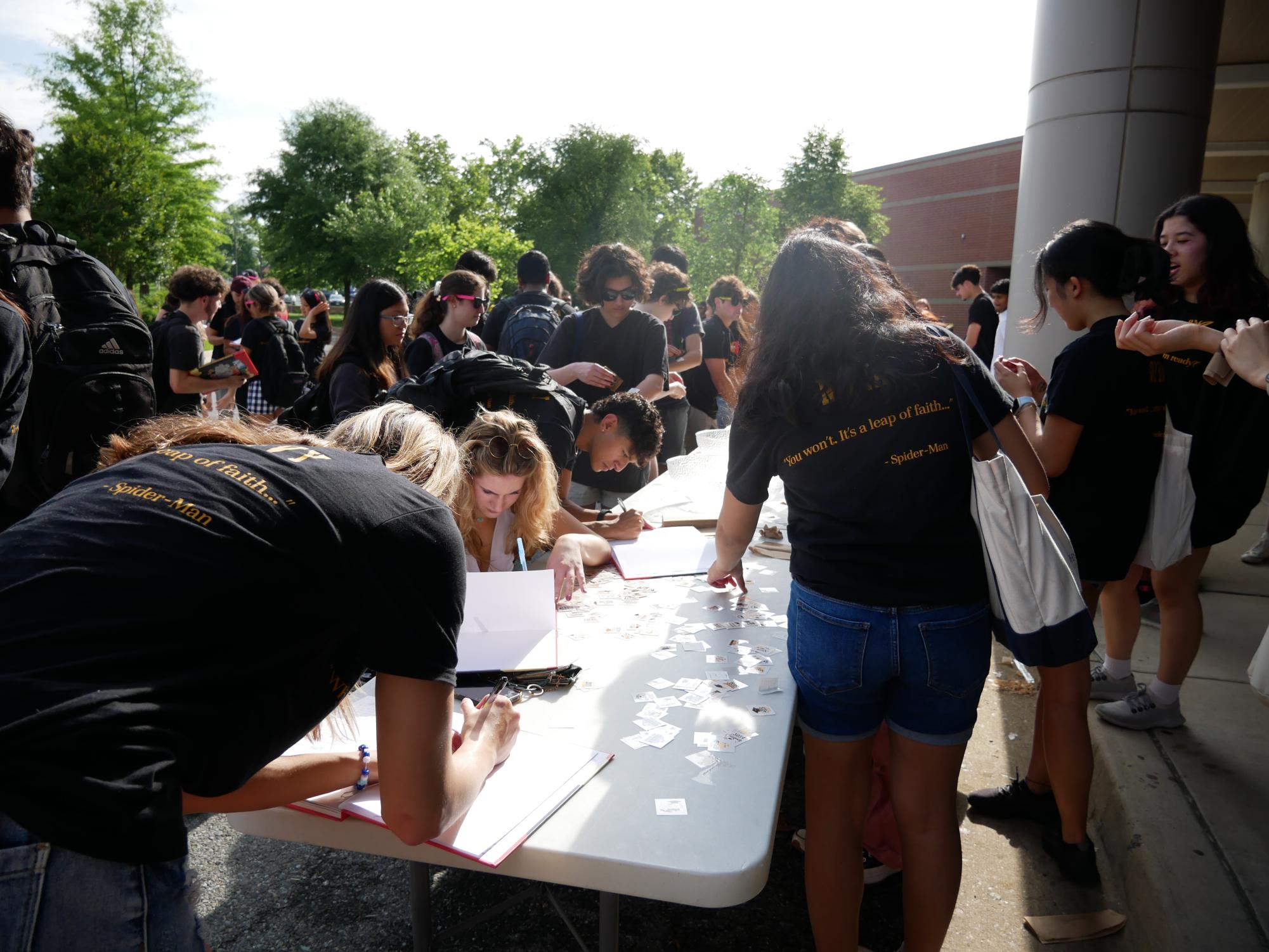Seniors Livia Venditti, Caroline Kaye and Zaki Ahmad sign each others yearbooks with the other seniors outside of the front doors of RM.