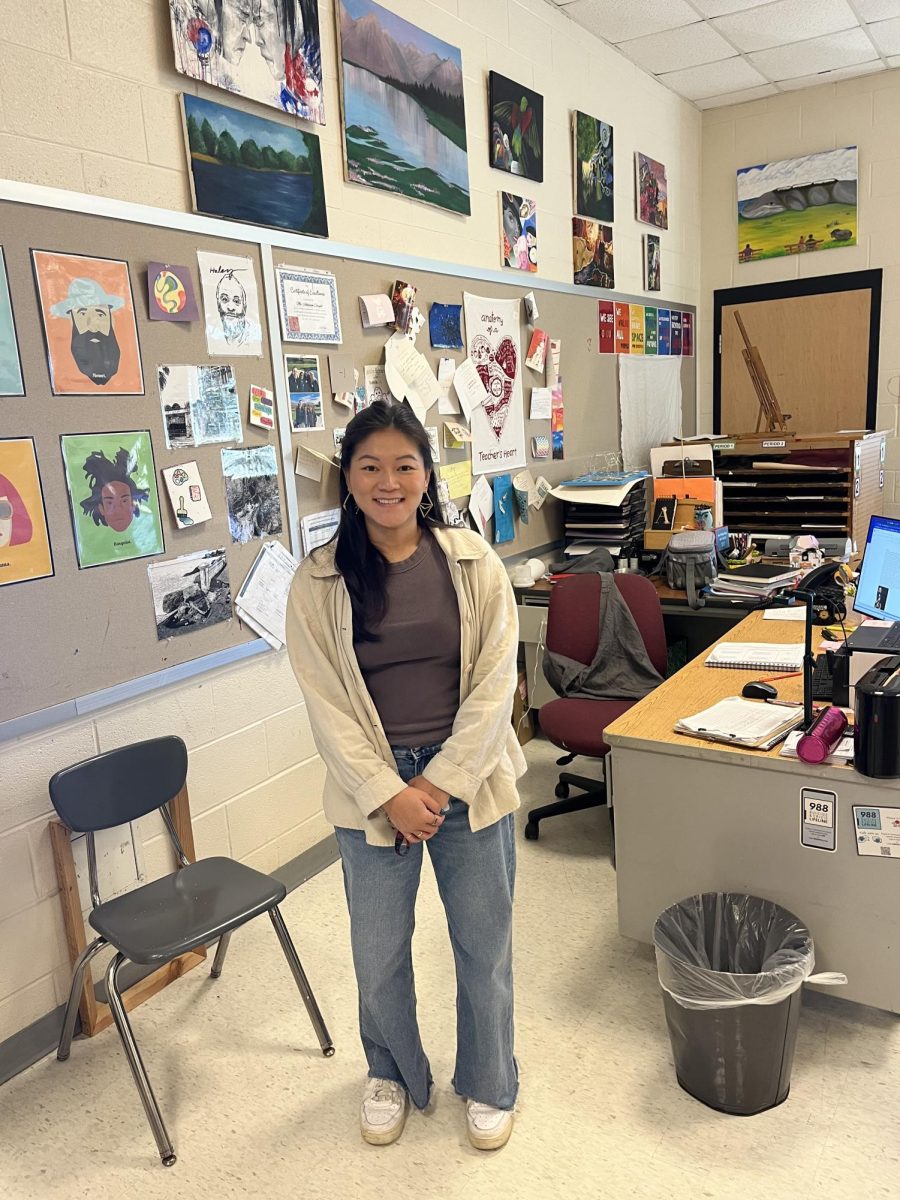 Ms. Coryell poses for a photo in front of her office, which is filled with pictures of student work.