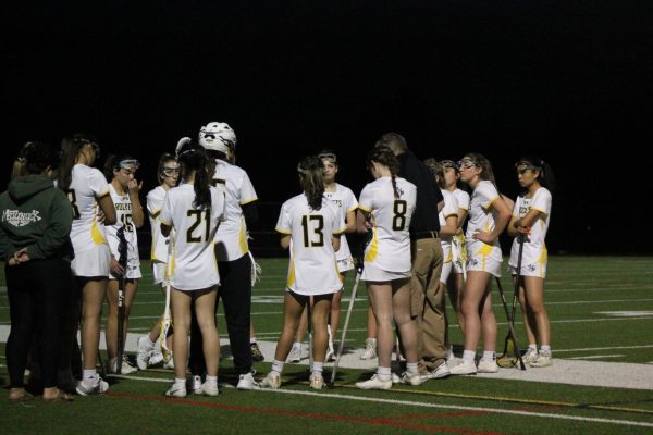 The girls varsity lacrosse team huddles during halftime of a game. 