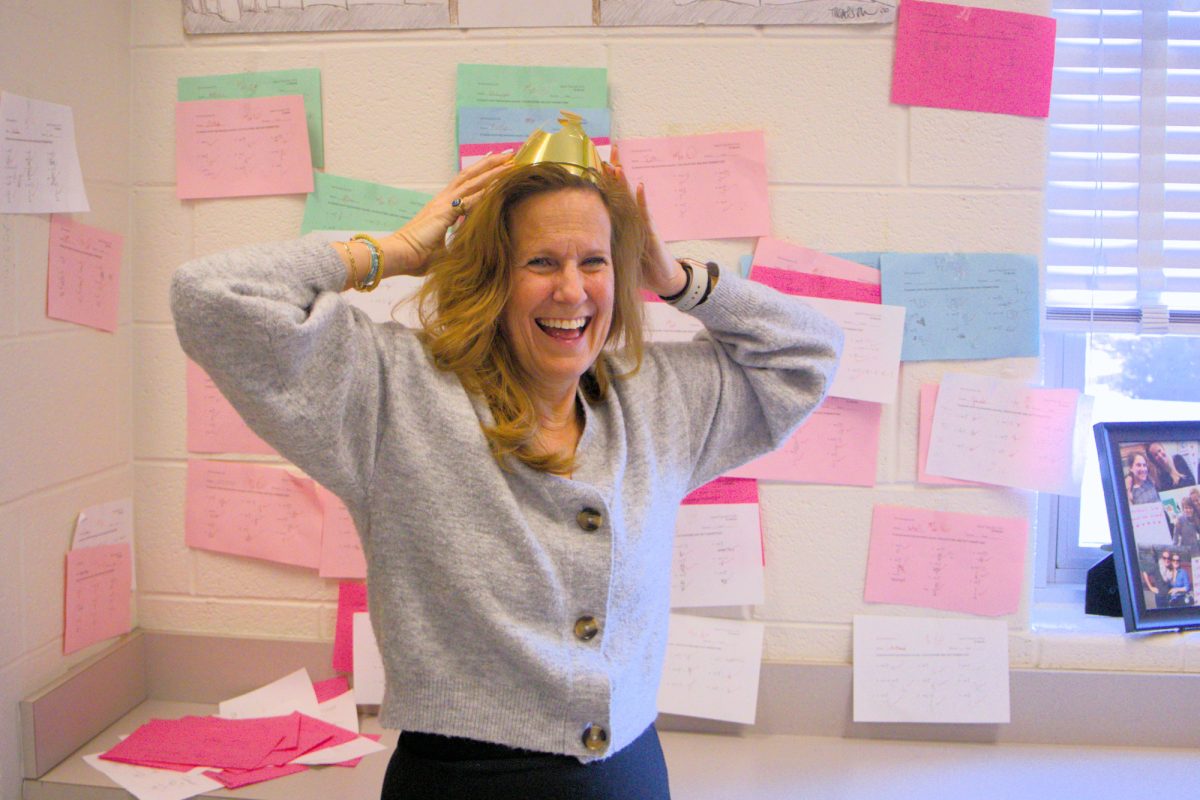 Ms. Goetz wears the crown given to the yearly “Speed Trig Queen” in front of the wall of students’ perfect scores. 