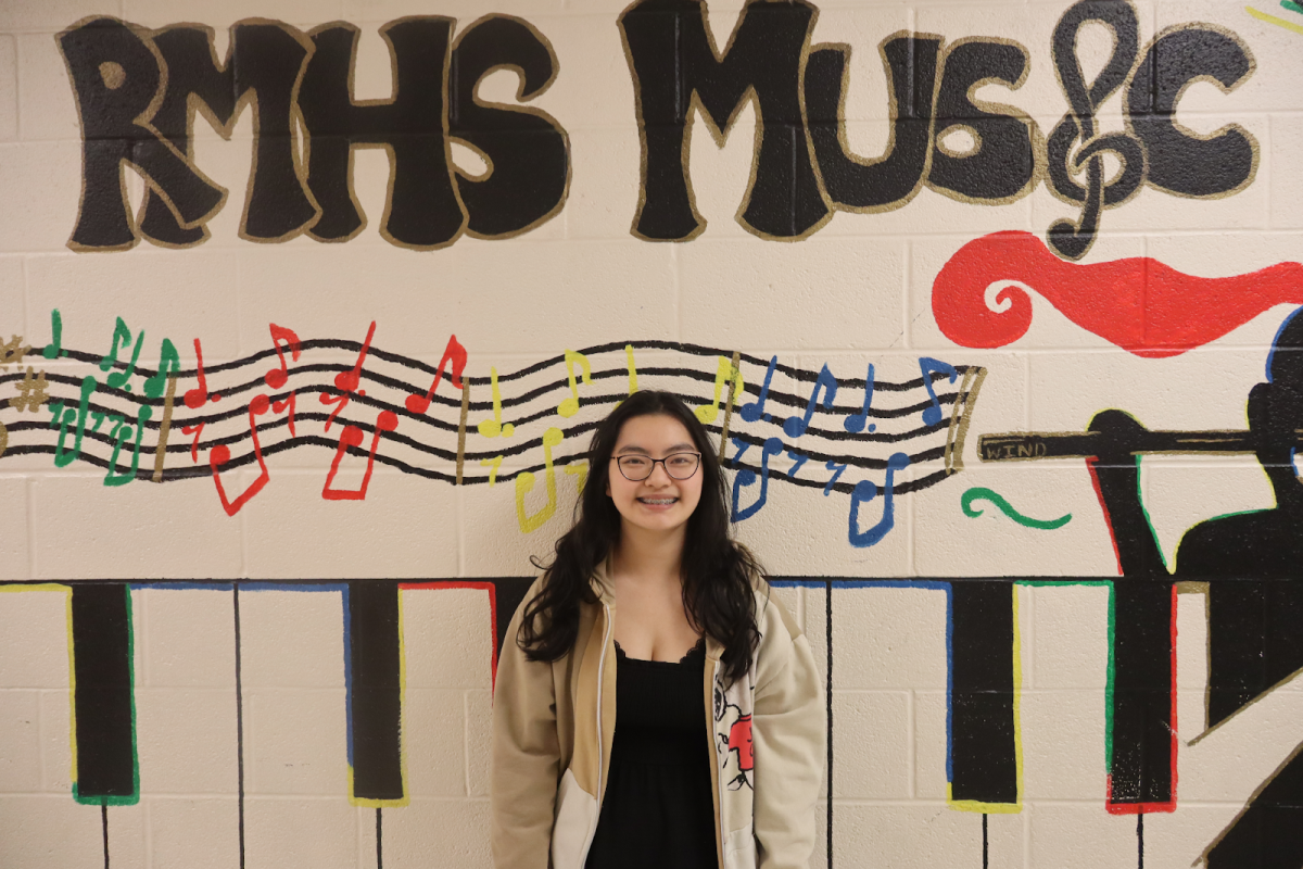 Senior Jasmine Chen, editor-in-chief of Fine Lines, poses in front of a mural in the chorus hallway.