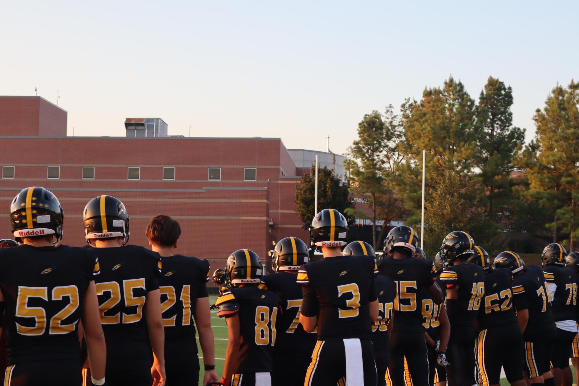 Members of the RM varsity football team stand together and watch from the sidelines during a game against Kennedy.