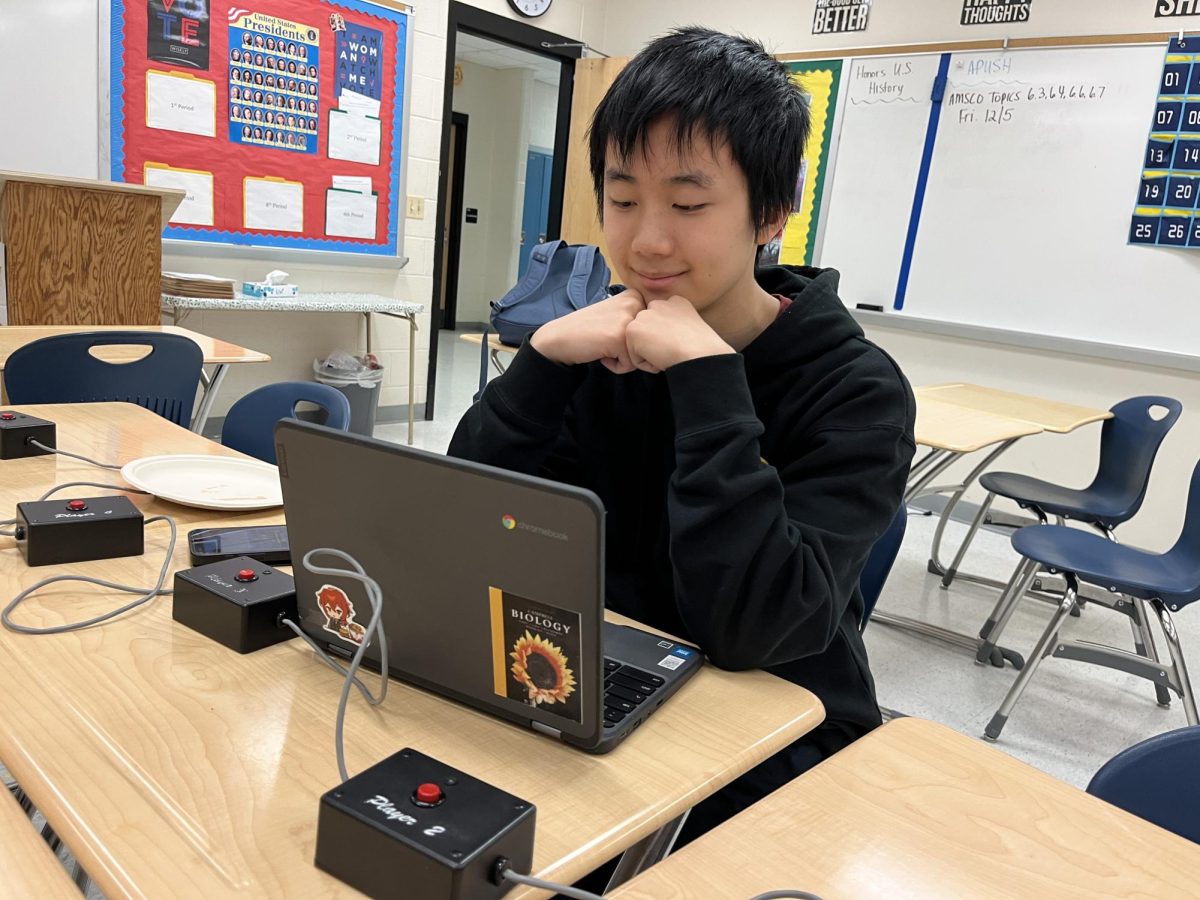 After the end of a quizbowl meeting, quizbowl captain, USABO semi-finalist, Science Olympiad captain and senior Andrew Zhao reads his textbook, "Campbell Biology." His chromebook is adorned with a sticker of the cover of the textbook that he won at a Science Olympiad tournament.