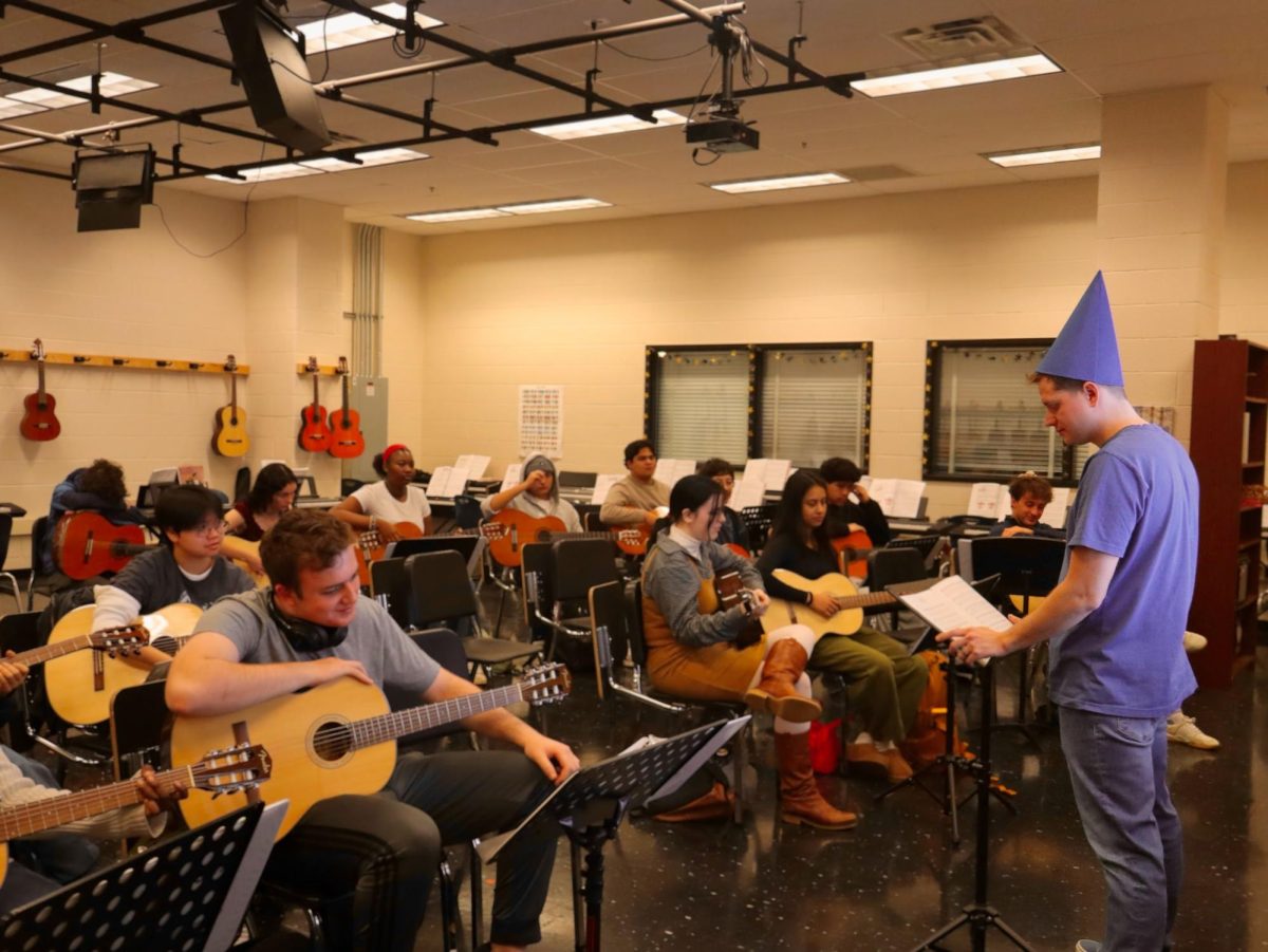 Mark Koons conducts his guitar-only ensemble class clad in a blue crayon costume, which matches most of the other teachers in the visual and performing arts department.