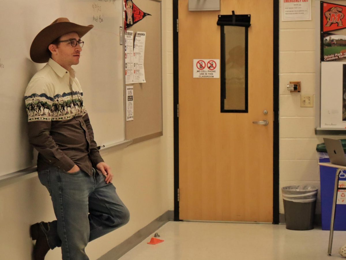 Social studies teacher Noah Grosfeld-Katz poses in front of his classroom, dressed as a Western cowboy. 