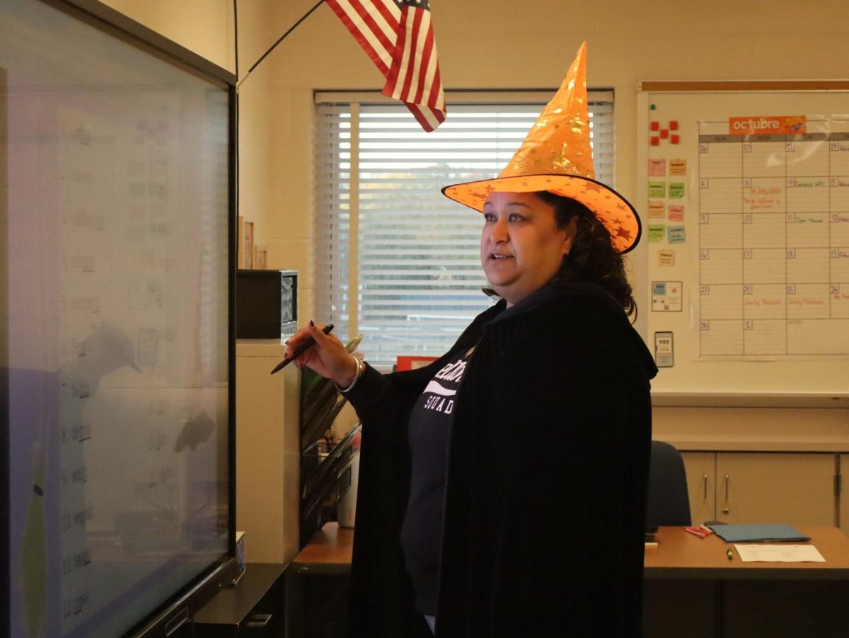 Spanish teacher Eirete De Jesus wears a witch costume to school, complete with a black cape and pointy hat.