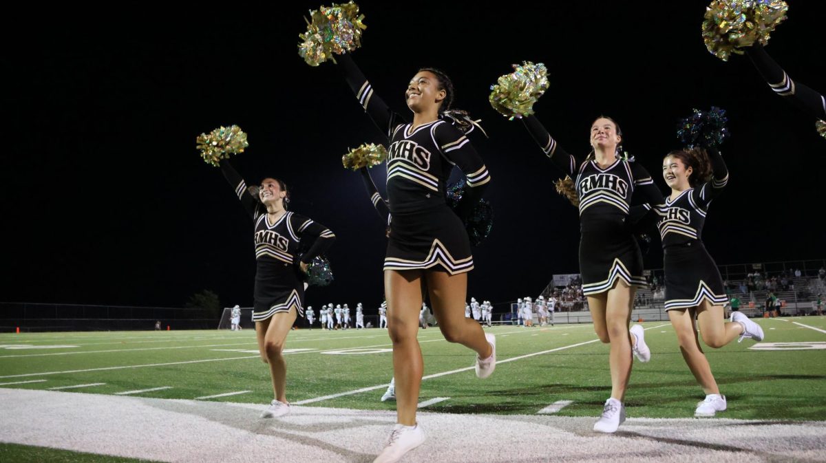 The poms team runs off the field after a halftime performance while they celebrate with one another.