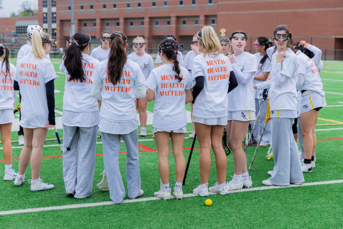 The girls varsity lacrosse team huddles up before a Morgan's Message dedication game, sporting shirts that read "Mental Health Matters."