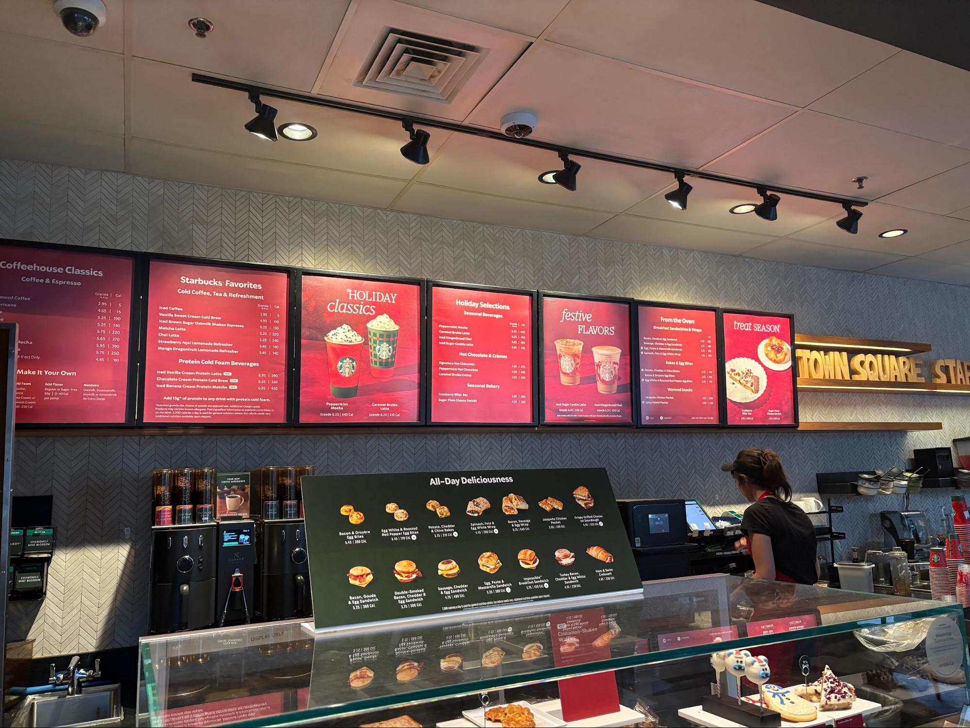 The menu at Starbucks is updated for winter, with red signs, decorations, holiday cups and holiday-themed treats in the display case.
