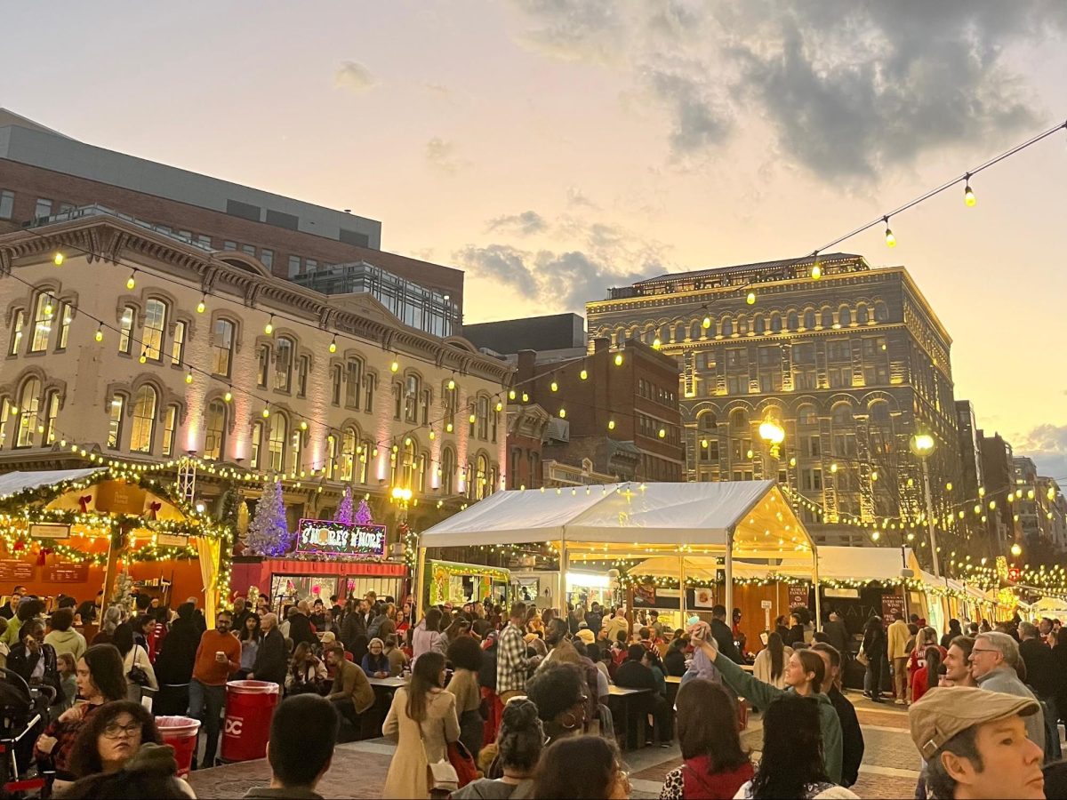 The warm lighting of the Dupont Circle Holiday Market blends with the bumble of people enjoying the shops, food and scenery, offering a cozy feeling against the grand buildings that surround the market. (Photo courtesy of Katie Mitchell)