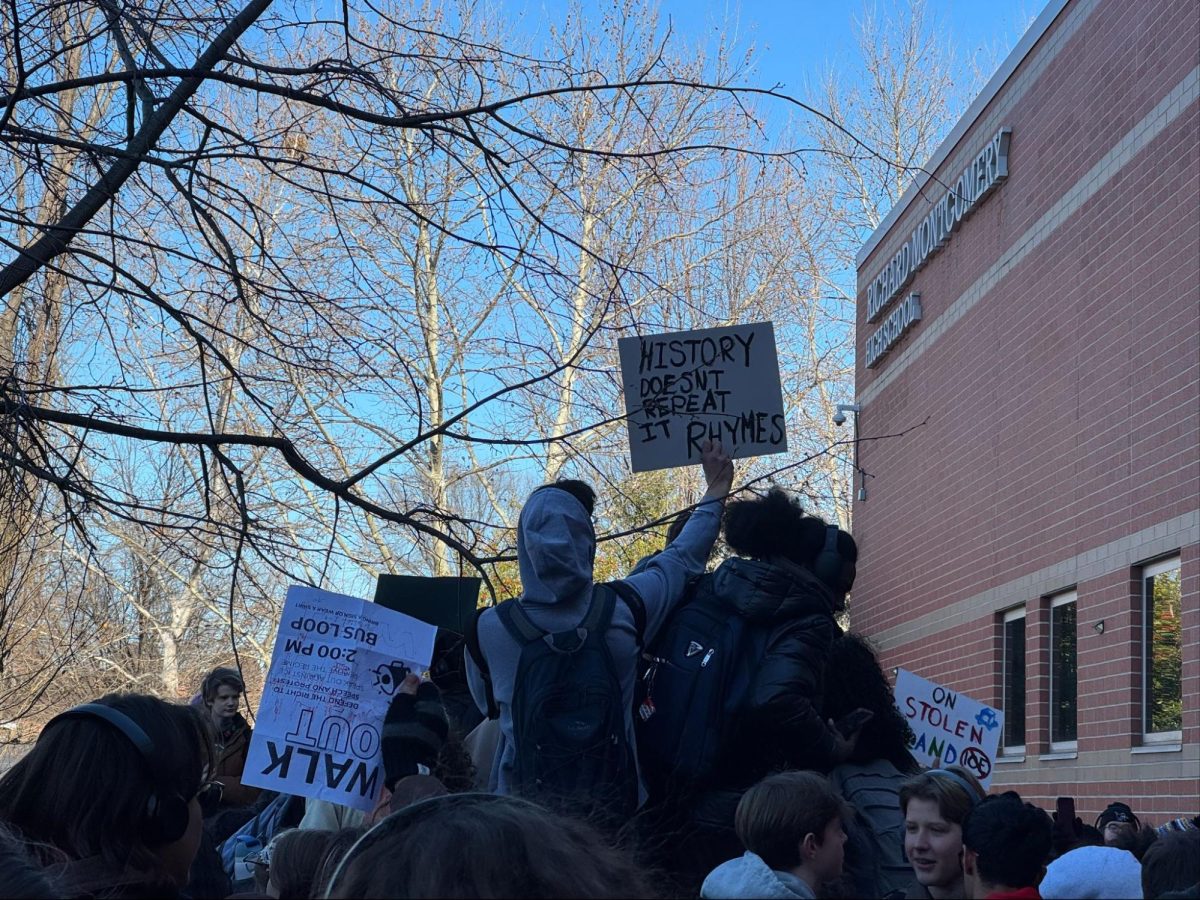 Students hold up signs in front of the school protesting ICE. 