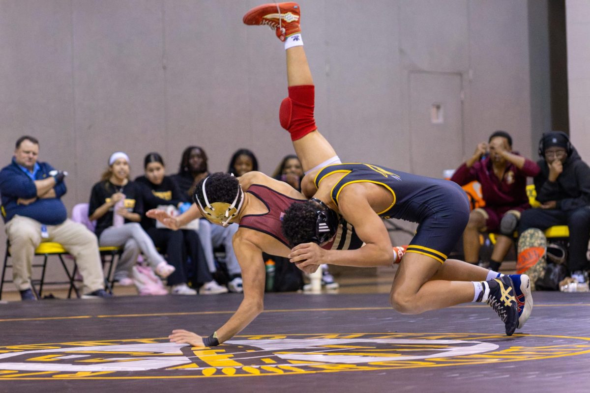 Junior Joey Womack slams his opponent to the mat, drawing reactions from the ongoing crowd.