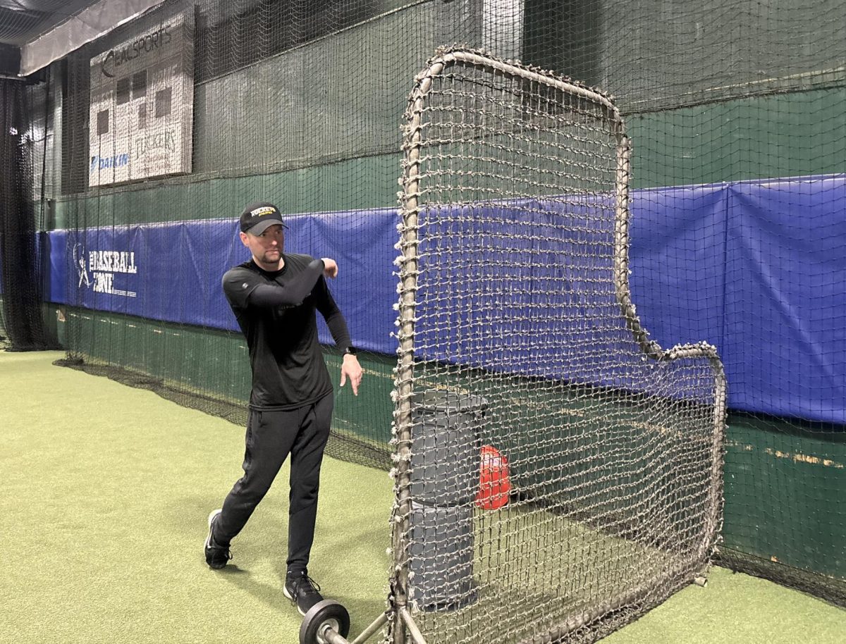 Coach Johnson tosses a pitch during winter workout batting practice.