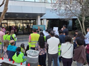 Community members wearing safety vests watch a live broadcast of the Montgomery County Board of Education meeting outside the MCPS BOE building in Rockville on March 26. Protesters gathered to voice concerns over the implementation of a regional magnet model and a controversial redistricting plan.