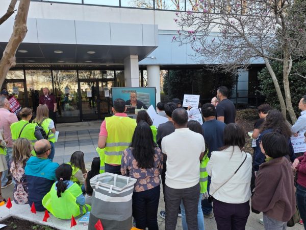 Community members wearing safety vests watch a live broadcast of the Montgomery County Board of Education meeting outside the MCPS BOE building in Rockville on March 26. Protesters gathered to voice concerns over the implementation of a regional magnet model and a controversial redistricting plan.