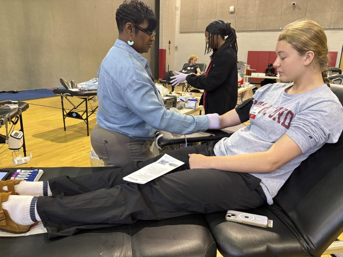  Junior Brooke Bennett watches as a volunteer cleanses her arm before drawing blood.